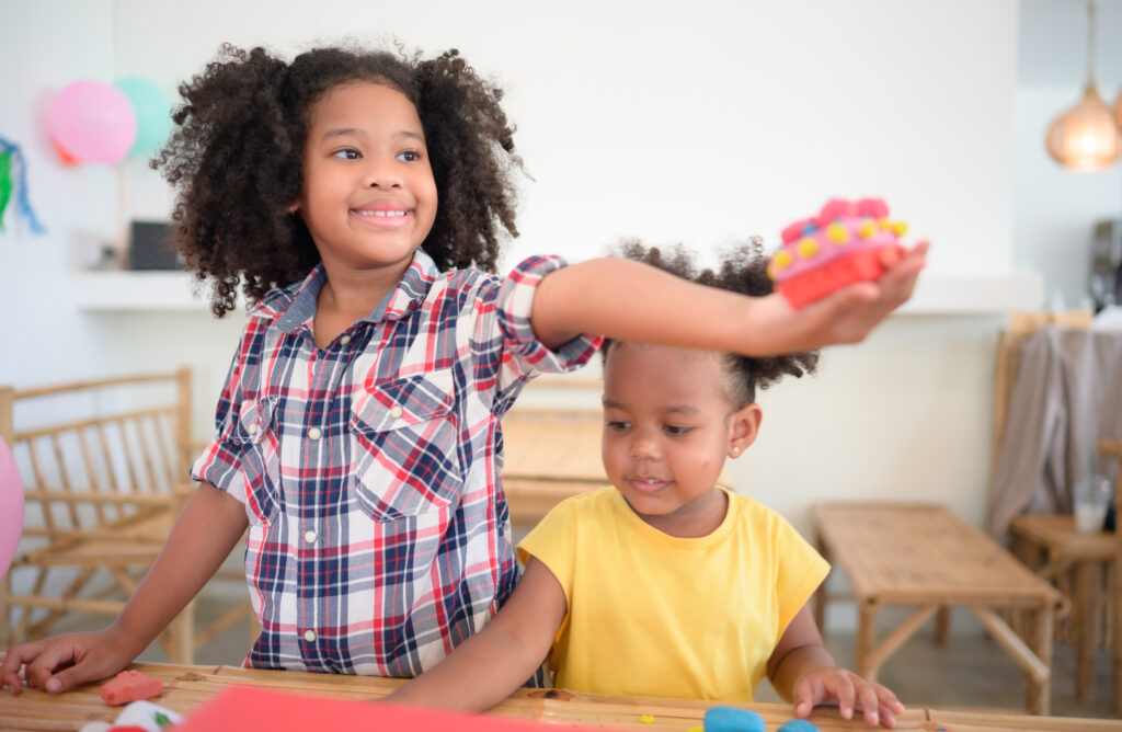 Two little girls Playing with plasticine in various shapes merrily